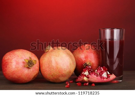 Ripe pomegranates with glass of pomegranate juice on red background