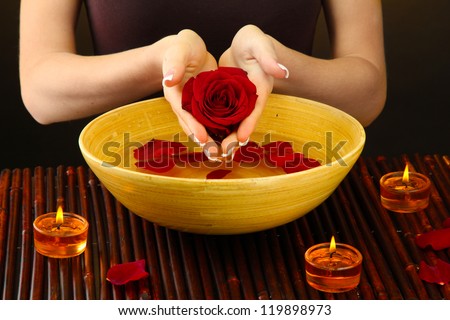 woman hands with wooden bowl of water with petals