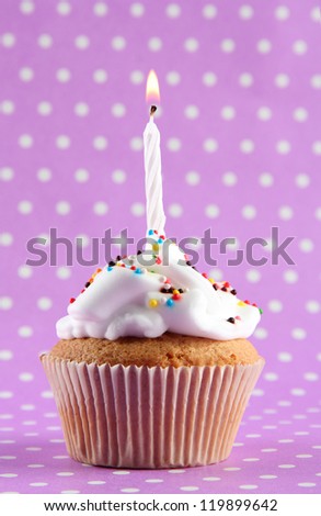 tasty birthday cupcake with candle, on purple background