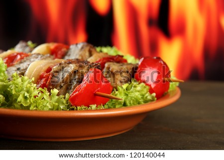 tasty grilled meat and vegetables on plate, on fire background