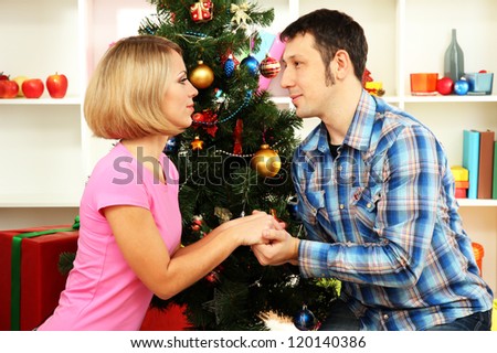 Young happy couple near a Christmas tree at home