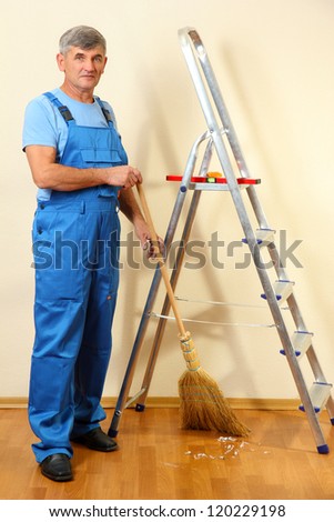 Handyman sweeping trash in room