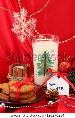 Cookies for Santa: Conceptual image of ginger cookies, milk and christmas decoration on red background