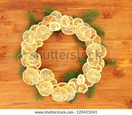 christmas wreath of dried lemons with fir tree, on wooden background