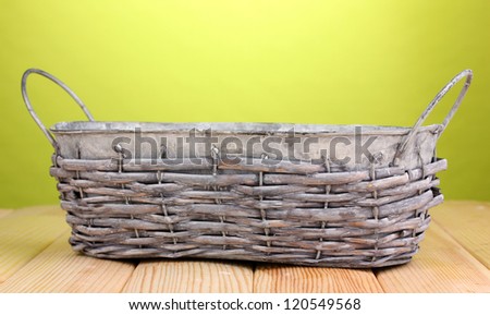 empty grey basket on wooden table on green background