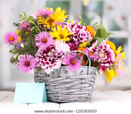 beautiful bouquet of bright flowers in basket on wooden table