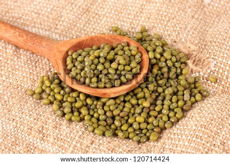 Mung beans over wooden spoon on the sackcloth background