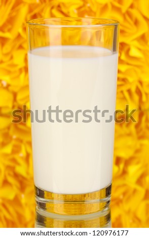 Glass of fresh new milk on decorative yellow background with reflection