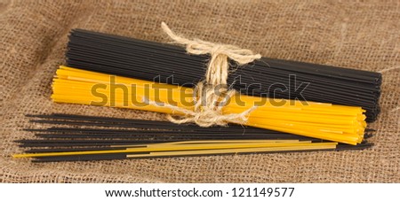 Black and yellow spaghetti on sackcloth background