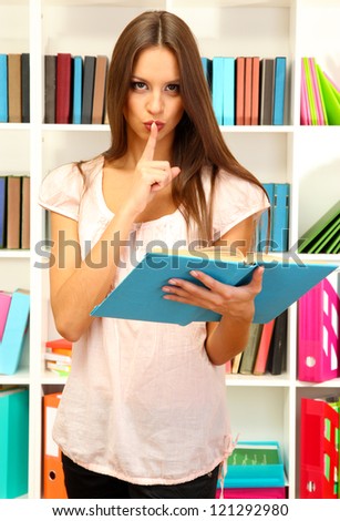 Young attractive female student reads book in library