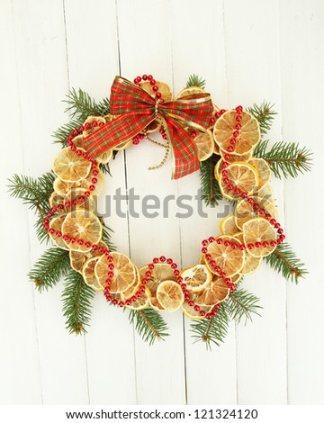 christmas wreath of dried lemons with fir tree and bow, on white wooden background