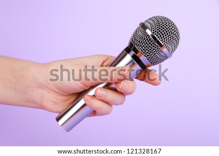 Silver microphone in hand on purple background