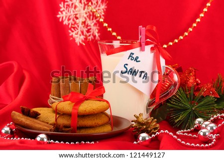 Cookies for Santa: Conceptual image of ginger cookies, milk and christmas decoration on red background