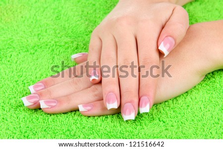 Woman hands with french manicure on green towel