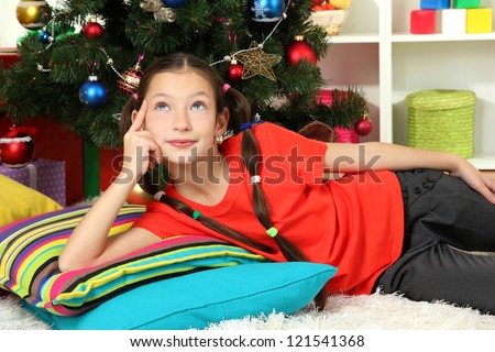 Little girl dreaming near christmas tree