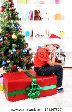 Little boy with big gift and clock in anticipation of New Year