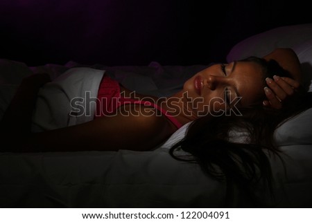 young beautiful woman sleeping in bed in dark bedroom
