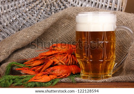 Tasty boiled crayfishes and beer on table on sackcloth background