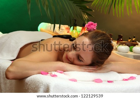 beautiful young woman in spa salon with spa stones, on green background