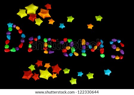 The word Dreams with colorful paper stars with dreams isolated on black