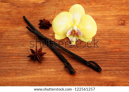 Vanilla pods and anise with flower, on brown wooden background