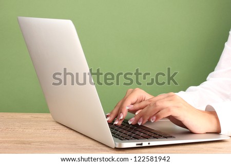 business woman\'s hands typing on laptop computer, on green background close-up
