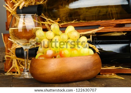 Wooden case with wine bottles, wineglass and grape close up