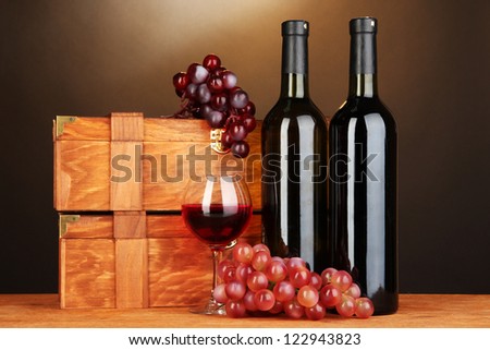 Wooden cases with wine bottles on wooden table on brown background
