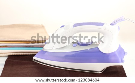 Flat electric iron and clothes isolated on white