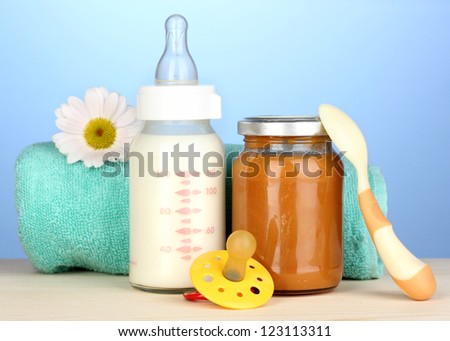 Baby food, bottle of milk and puree  on blue background