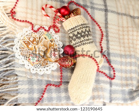 Warm knitted sock with gifts on plaid close-up