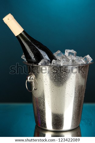 Bottle of wine in ice bucket on darck blue background