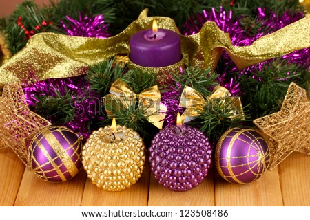 Christmas composition  with candles and decorations in purple and gold colors on wooden background