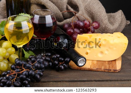 bottles and glasses of wine, cheese and grapes on grey background
