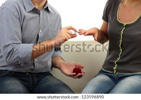 Young man making offer of marriage and giving ring to woman isolated on white