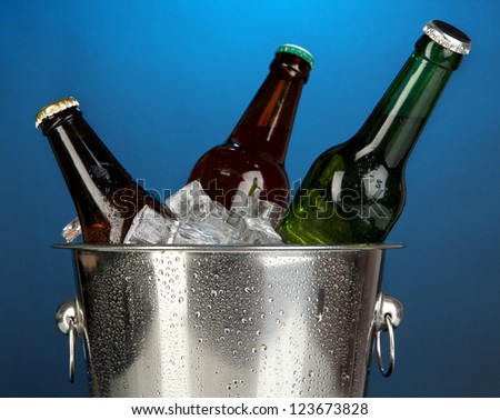 Beer bottles in ice bucket on darck blue background