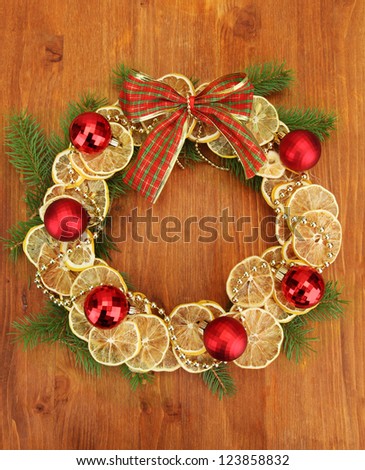 christmas wreath of dried lemons with fir tree and balls, on wooden background
