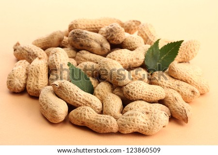tasty peanuts with green leaves, on beige background