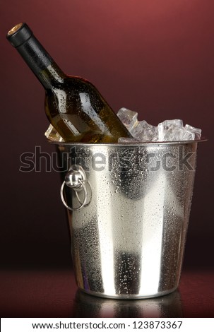 Bottle of wine in ice bucket on darck red background