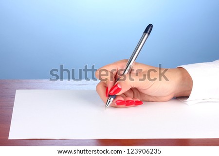 Hands writing on  paper on blue background