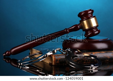 Gavel, handcuffs and book on law on blue background
