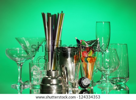 Cocktail shaker and glasses on color background