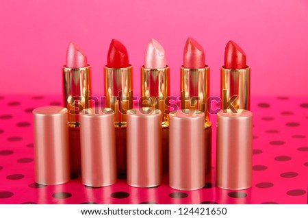 Lipsticks on table on pink background