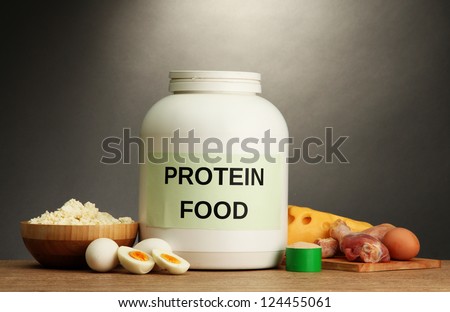 jar of protein powder and food with protein, on grey background
