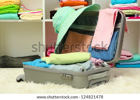 Open silver suitcase with clothing in room