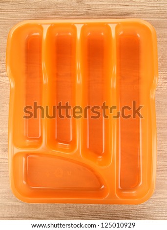 Orange plastic cutlery tray on wooden table