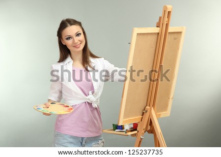 beautiful young woman painter at work, on grey background