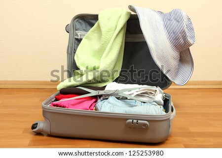 Open silver suitcase with clothing in room