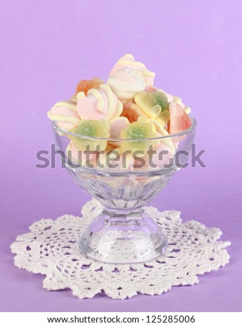 Gentle marshmallow in glass vase on purple background