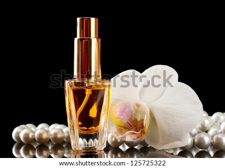 women\'s perfume in beautiful bottle and orchid flowers, on black background